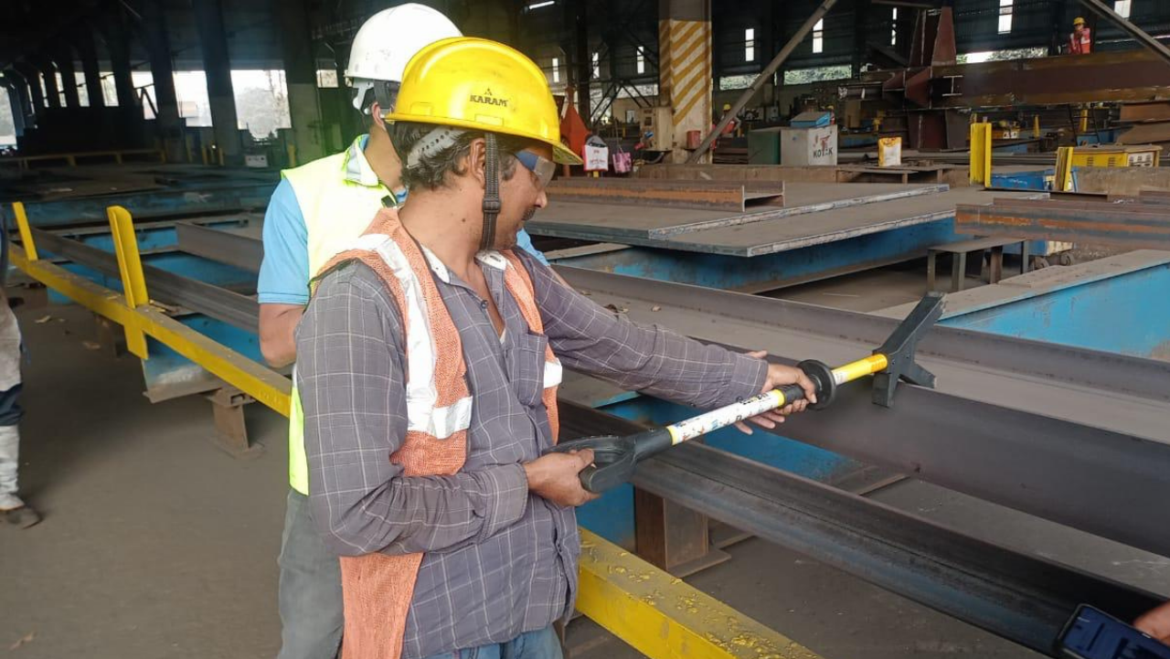 Workers using PSC tools to guide a suspended industrial load